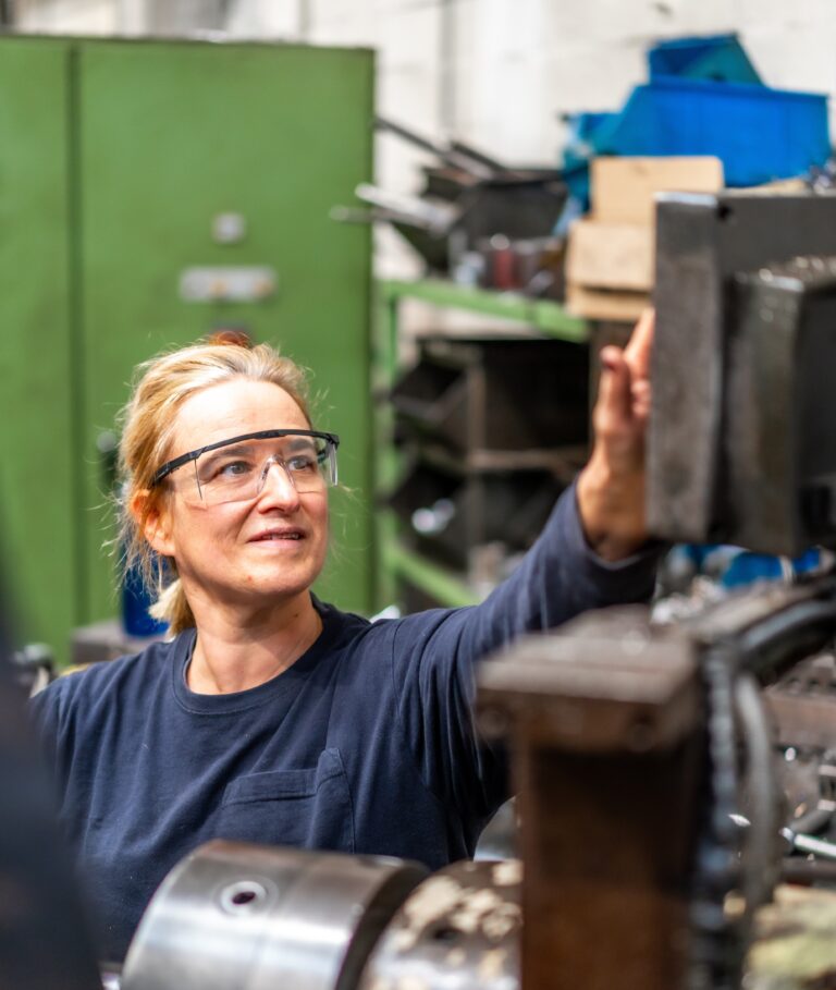 Female factory worker operator working in the control sector on a metal milling machine, industrial factory