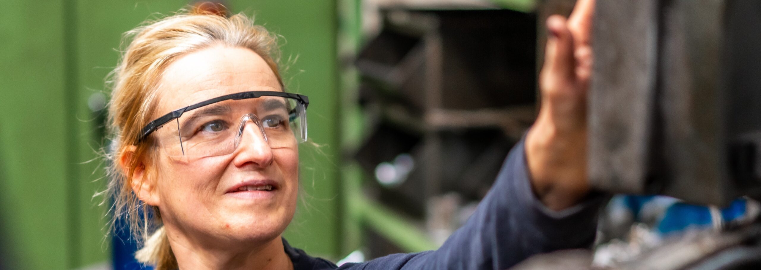 Female factory worker operator working in the control sector on a metal milling machine, industrial factory